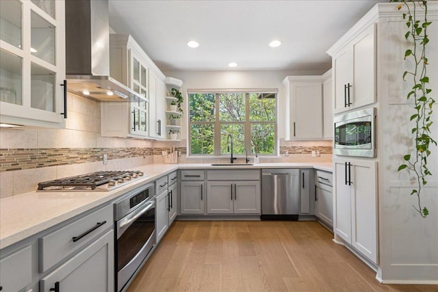 15213 Falconhead Grove Loop, Austin, TX 78738 - kitchen with stainless steel appliances, wall chimney exhaust hood, light wood-type flooring, tasteful backsplash, and recessed lighting