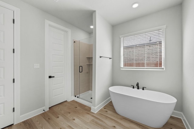 full bath with a freestanding bath, baseboards, a shower stall, and wood finished floors