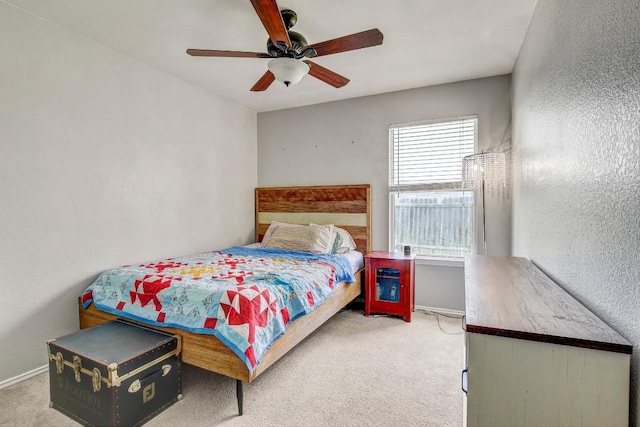 bedroom featuring a ceiling fan, baseboards, a textured wall, and carpet