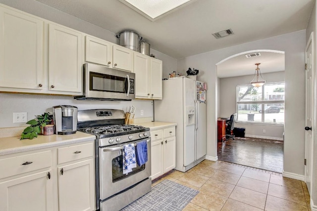 kitchen with white cabinetry, arched walkways, appliances with stainless steel finishes, and visible vents