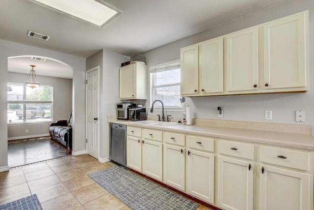 kitchen with visible vents, a healthy amount of sunlight, stainless steel dishwasher, a sink, and arched walkways