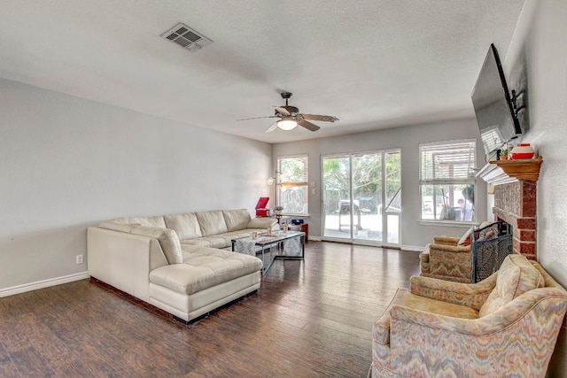 living room with wood finished floors, visible vents, a ceiling fan, baseboards, and a fireplace