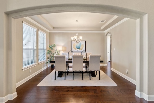 3817 Benetton Way, Leander, TX 78641 - dining space with arched walkways, dark wood finished floors, a chandelier, a raised ceiling, and ornamental molding