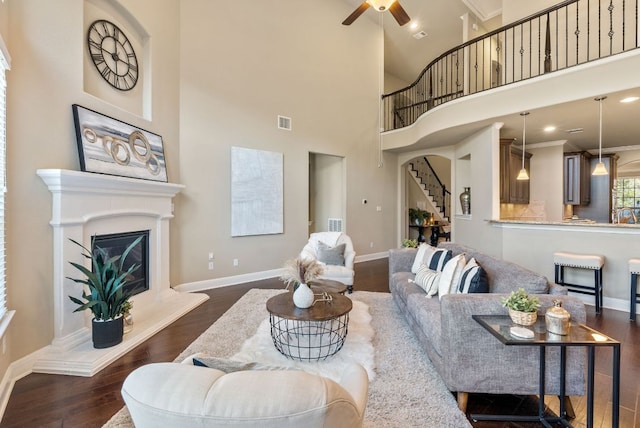 3817 Benetton Way, Leander, TX 78641 - living area featuring stairs, dark wood-type flooring, ceiling fan, a glass covered fireplace, and a towering ceiling