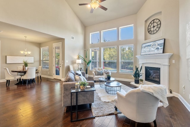 3817 Benetton Way, Leander, TX 78641 - living room with dark wood-style floors, ceiling fan, a towering ceiling, a glass covered fireplace, and baseboards