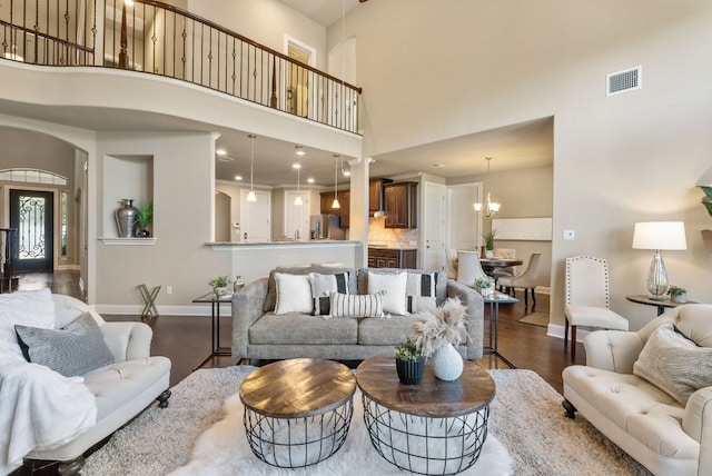 3817 Benetton Way, Leander, TX 78641 - living room featuring a towering ceiling, dark wood-type flooring, baseboards, a chandelier, and arched walkways