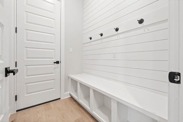 mudroom with light wood finished floors and wood walls