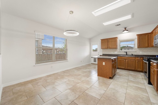 kitchen featuring brown cabinetry, a kitchen island, a sink, and stainless steel appliances