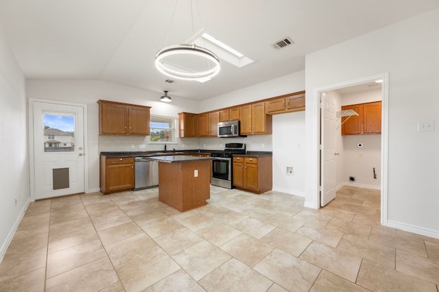 kitchen with a center island, dark countertops, visible vents, brown cabinets, and appliances with stainless steel finishes