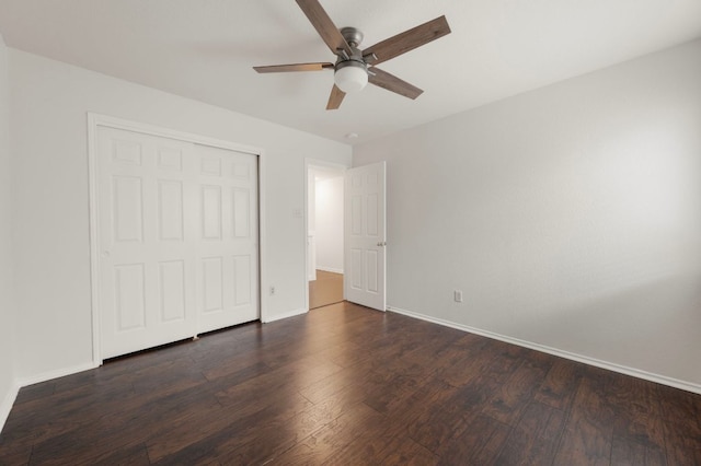 unfurnished bedroom featuring dark wood-type flooring, a closet, baseboards, and a ceiling fan