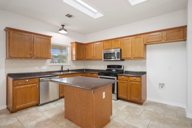 kitchen featuring a kitchen island, visible vents, brown cabinetry, stainless steel appliances, and a sink