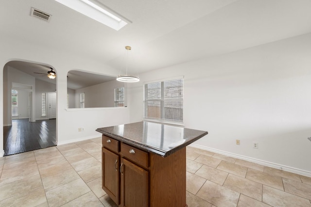 kitchen with visible vents, arched walkways, ceiling fan, pendant lighting, and a kitchen island