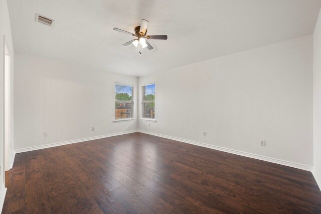 spare room with dark wood-type flooring, visible vents, baseboards, and ceiling fan
