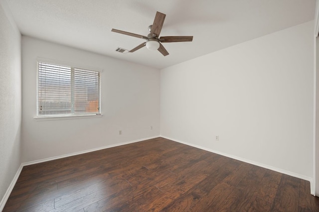 empty room with dark wood-type flooring, ceiling fan, baseboards, and visible vents