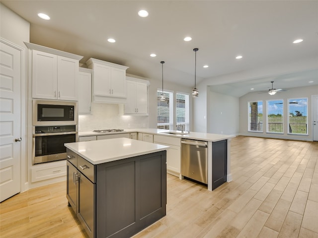 kitchen with a healthy amount of sunlight, a peninsula, stainless steel appliances, and a kitchen island