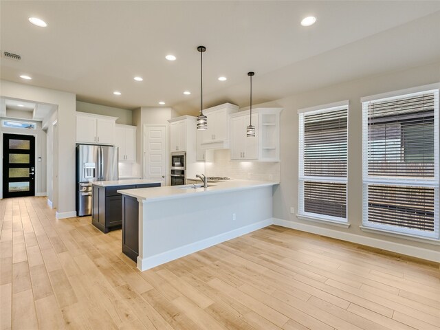 131 Plumbago Loop, Bastrop, TX 78602 - kitchen featuring stainless steel appliances, open shelves, light countertops, visible vents, and a peninsula
