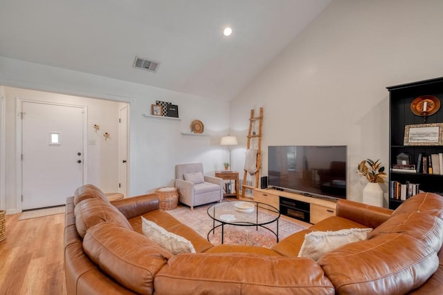 living area featuring wood finished floors, high vaulted ceiling, and visible vents