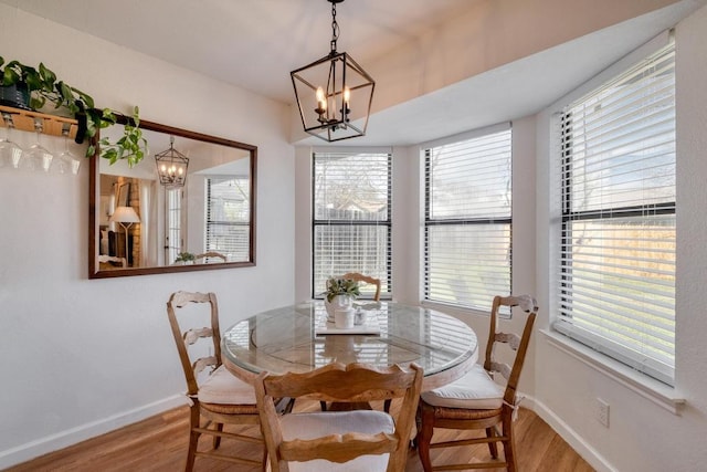 dining room with a notable chandelier, baseboards, and wood finished floors