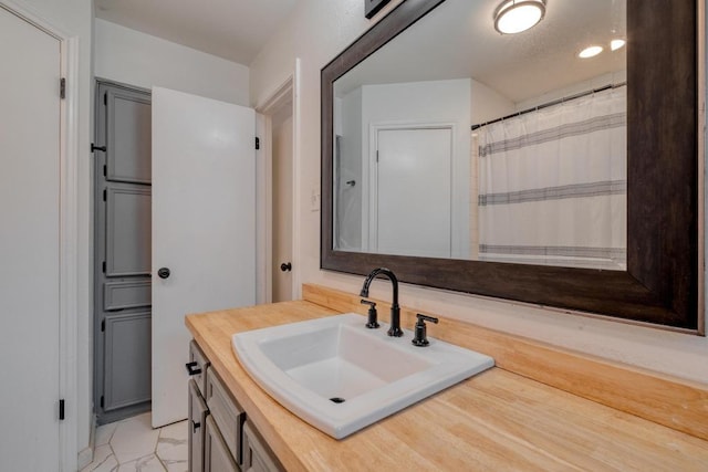 full bath with marble finish floor and vanity