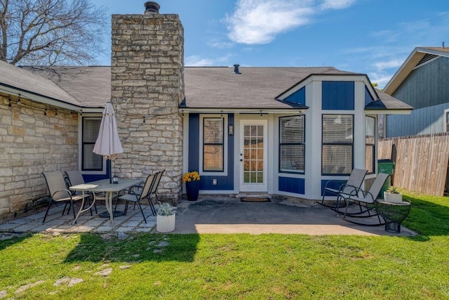 back of house featuring a patio area, fence, a shingled roof, and a lawn
