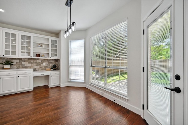7802 Cheno Cortina Trl, Austin, TX 78749 - unfurnished dining area with baseboards, built in desk, and dark wood finished floors