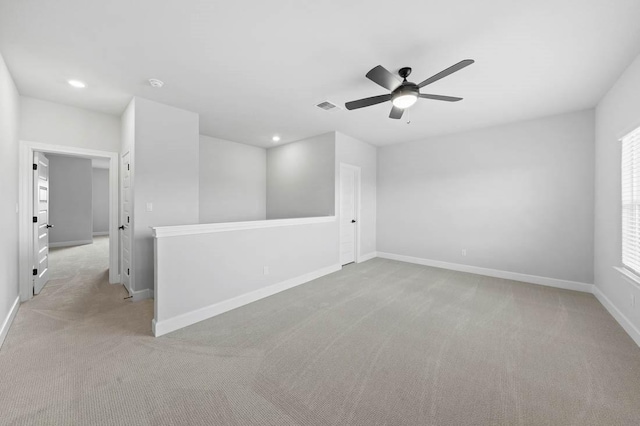 empty room with light colored carpet, visible vents, baseboards, and ceiling fan