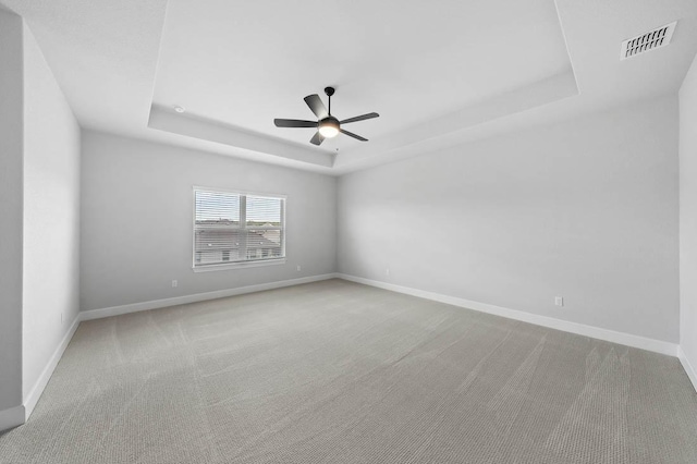 unfurnished room featuring carpet, visible vents, baseboards, and a raised ceiling