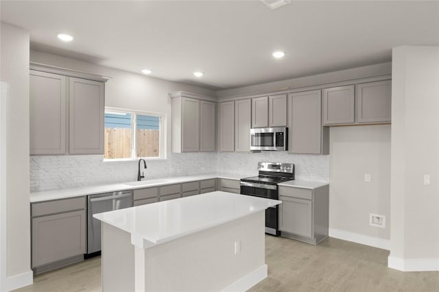 9708 Petrichor Blvd, Manor, TX 78653 - kitchen featuring gray cabinetry, appliances with stainless steel finishes, a sink, backsplash, and a center island