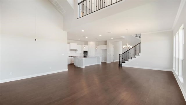 9709 Boathouse Dr, Austin, TX 78744 - unfurnished living room with stairway, dark wood-style floors, baseboards, a chandelier, and a towering ceiling