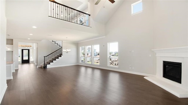 9709 Boathouse Dr, Austin, TX 78744 - unfurnished living room with stairs, a high ceiling, a ceiling fan, dark wood-style floors, and a glass covered fireplace