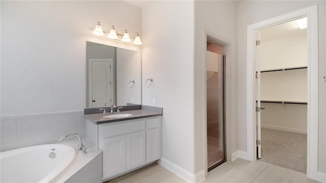 9709 Boathouse Dr, Austin, TX 78744 - full bathroom featuring vanity, a walk in closet, a bath, and baseboards