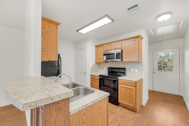 128 2nd Ave, Taylor, TX 76574 - kitchen featuring stainless steel microwave, electric range, freestanding refrigerator, light countertops, and a peninsula