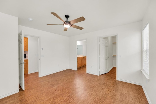 128 2nd Ave, Taylor, TX 76574 - unfurnished bedroom featuring light wood-style flooring, a walk in closet, ensuite bath, ceiling fan, and a closet