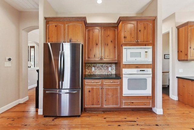 201 Mcconnell Dr, West Lake Hills, TX 78746 - kitchen featuring white appliances, decorative backsplash, light wood-style floors, brown cabinetry, and arched walkways