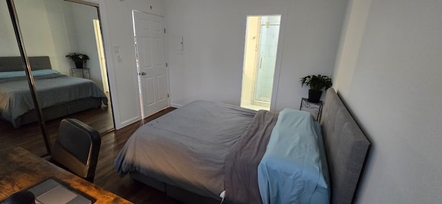 bedroom featuring baseboards, a closet, ensuite bath, and wood finished floors
