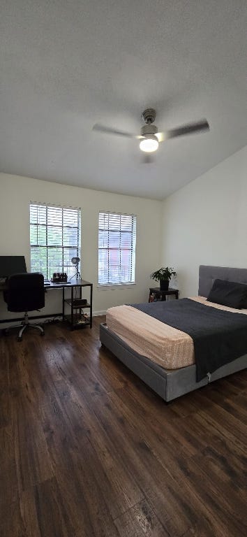 bedroom featuring a ceiling fan, dark wood finished floors, and multiple windows