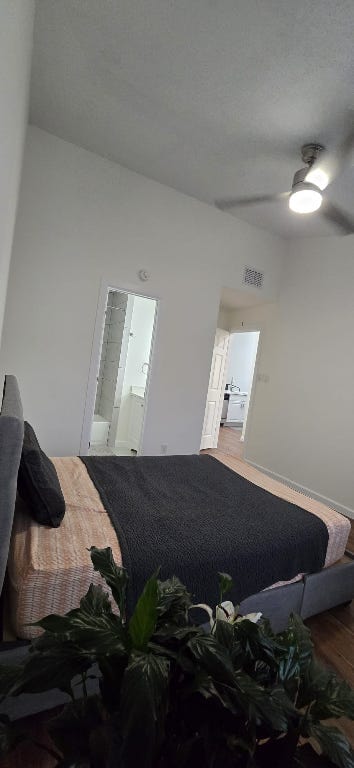 bedroom with a ceiling fan, wood finished floors, and visible vents