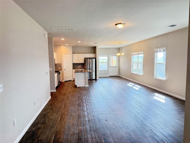 3409 Brywood Dr, Pflugerville, TX 78660 - unfurnished living room featuring baseboards, dark wood-type flooring, and a chandelier