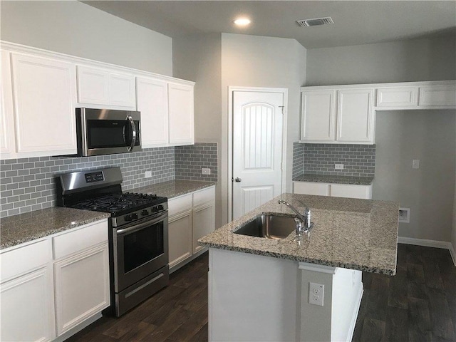 3409 Brywood Dr, Pflugerville, TX 78660 - kitchen featuring appliances with stainless steel finishes, a sink, light stone countertops, white cabinets, and a center island with sink