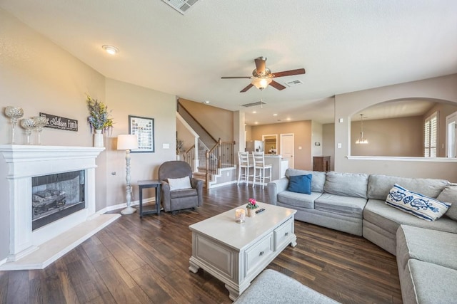 3505 Grail Hollows Rd, Pflugerville, TX 78660 - living area featuring dark wood-type flooring, a ceiling fan, stairs, a glass covered fireplace, and baseboards