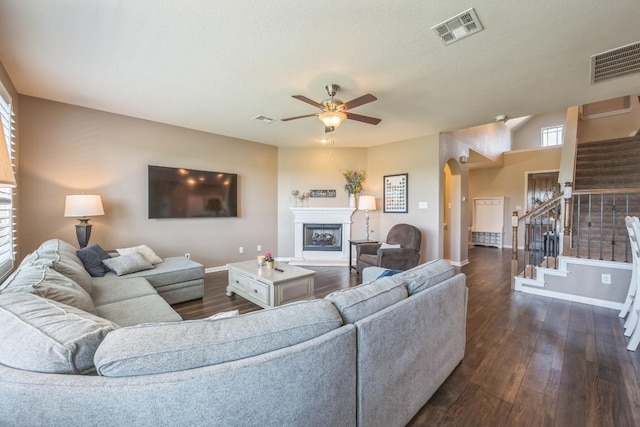 3505 Grail Hollows Rd, Pflugerville, TX 78660 - living room featuring arched walkways, baseboards, a ceiling fan, a fireplace, and dark wood-style floors