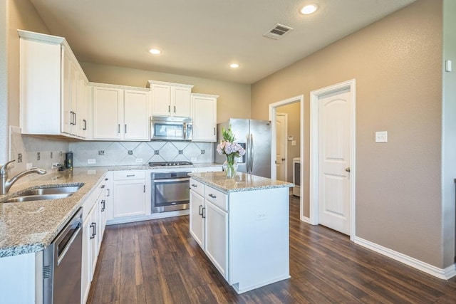 3505 Grail Hollows Rd, Pflugerville, TX 78660 - kitchen with appliances with stainless steel finishes, a sink, dark wood finished floors, tasteful backsplash, and white cabinetry