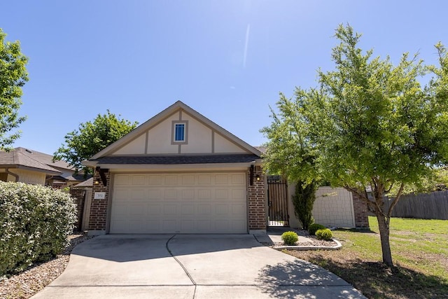 702 Silo St, San Marcos, TX 78666 - tudor-style house with driveway, brick siding, an attached garage, and a gate