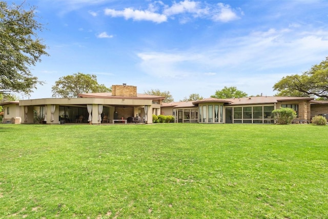 901 Blaylock Dr, Salado, TX 76571 - rear view of house with a sunroom, a chimney, a yard, and stucco siding