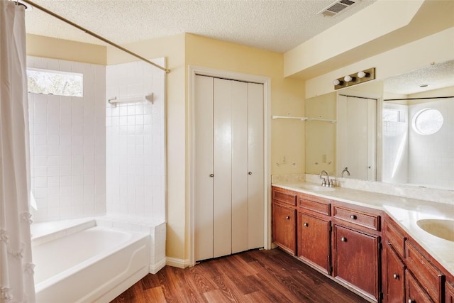 19 Deerfield Dr Unit 2, Wimberley, TX 78676 - bathroom featuring wood finished floors, double vanity, a textured ceiling, and shower / bath combination