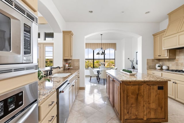 219 Jack Nicklaus Dr, Austin, TX 78738 - kitchen with appliances with stainless steel finishes, cream cabinets, arched walkways, a chandelier, and tasteful backsplash