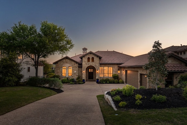 219 Jack Nicklaus Dr, Austin, TX 78738 - mediterranean / spanish-style home featuring stone siding, an attached garage, driveway, a tile roof, and a front yard