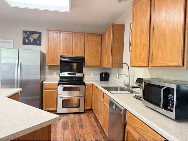 2201 Ezra Ct, Cedar Park, TX 78613 - kitchen with appliances with stainless steel finishes, a sink, range hood, wood finished floors, and light countertops