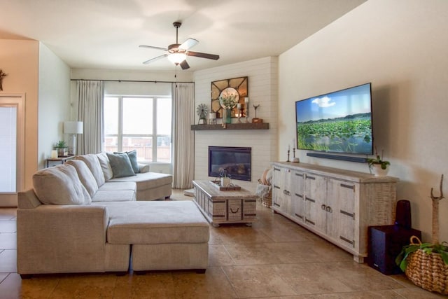 tiled living area featuring ceiling fan and a glass covered fireplace