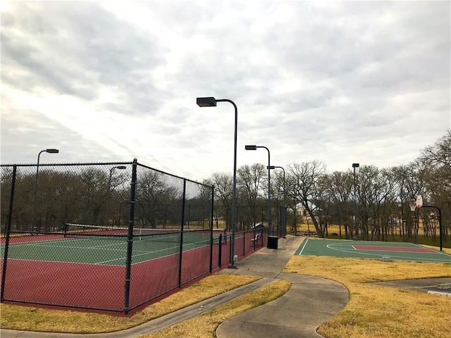 view of basketball court featuring a tennis court and fence
